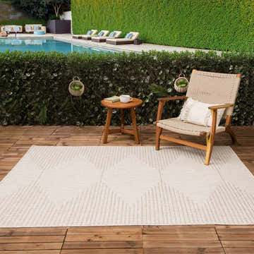 Outdoor patio scene with Stephan Beige rug, wood chair, side table, and pool in the background. Roomscene-Rectangle