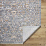 Close-up of the Bayram Area Rug. Gray, ivory, and brown floral pattern. Machine-woven polyester rug with folded corner. Fold