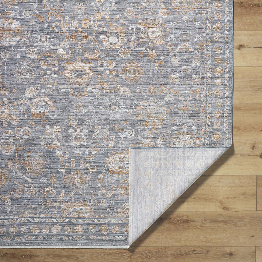 Close-up of the Bayram Area Rug. Gray, ivory, and brown floral pattern. Machine-woven polyester rug with folded corner. Fold