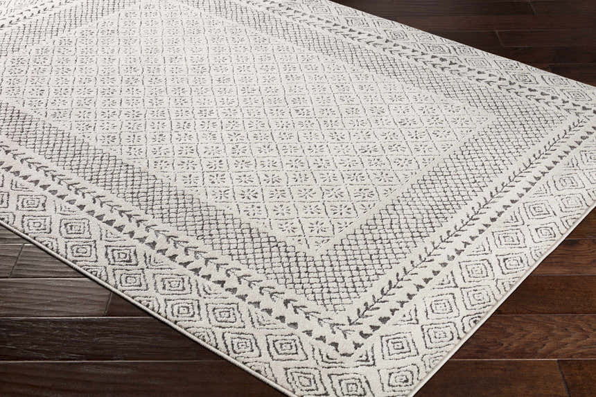 Close up of the Livabliss Bahar BHR-2321 area rug. Off white rug with a charcoal geometric and floral pattern. Corner
