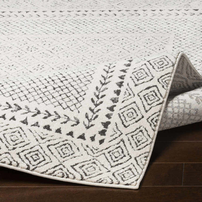 Close-up of the Livabliss Bahar BHR-2321 area rug, showing its charcoal and off-white geometric pattern and machine-woven texture. Fold