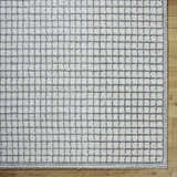 Close-up of the Balint Area Rug featuring a charcoal grid pattern on light gray, machine-woven texture. Corner