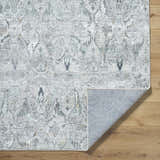Close-up of the Bryony Area Rug, a farmhouse style rug in light silver, silver gray, and slate blue with a traditional pattern. Fold