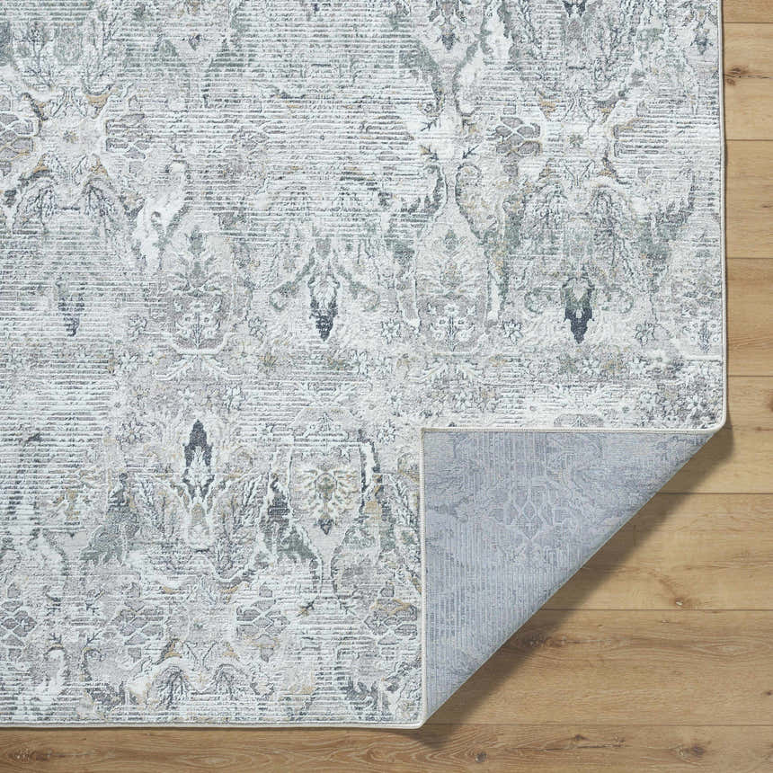 Close-up of the Bryony Area Rug, a farmhouse style rug in light silver, silver gray, and slate blue with a traditional pattern. Fold