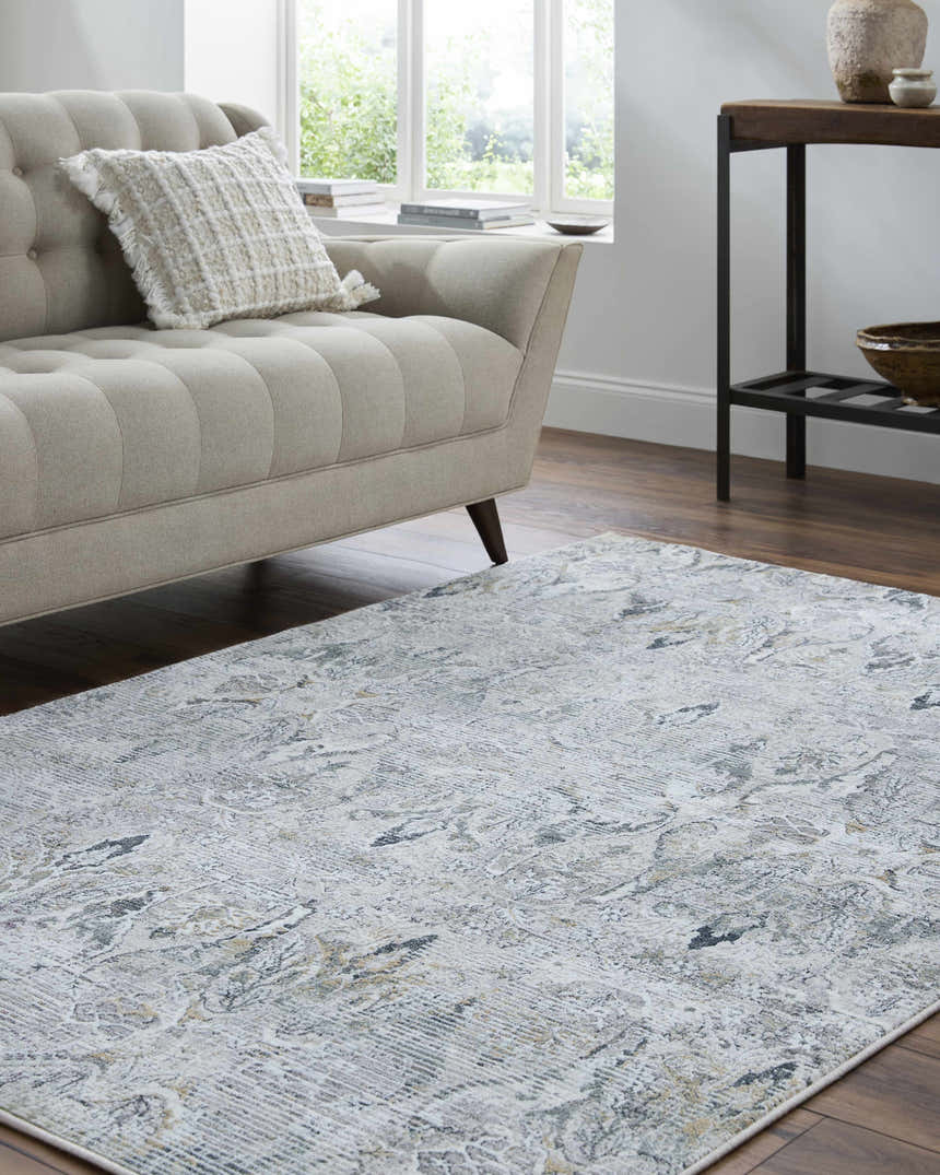 Living room scene with a Bryony Area Rug in light silver, gray, and blue under a beige sofa. Roomscene-Rectangle