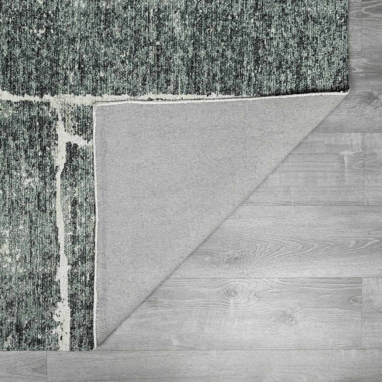 Close-up of the Janek II Modern Abstract Area Rug showing its green, black, and white abstract design and hand-tufted texture. Fold