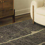Close-up of a Janek II Modern Abstract Area Rug in a living room with a wood cabinet and cream armchair. Roomscene-Rectangle