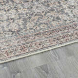 Close-up of the beige, dark red, and green Collins Avenue III Vintage Damask Area Rug on gray wood flooring. Pile