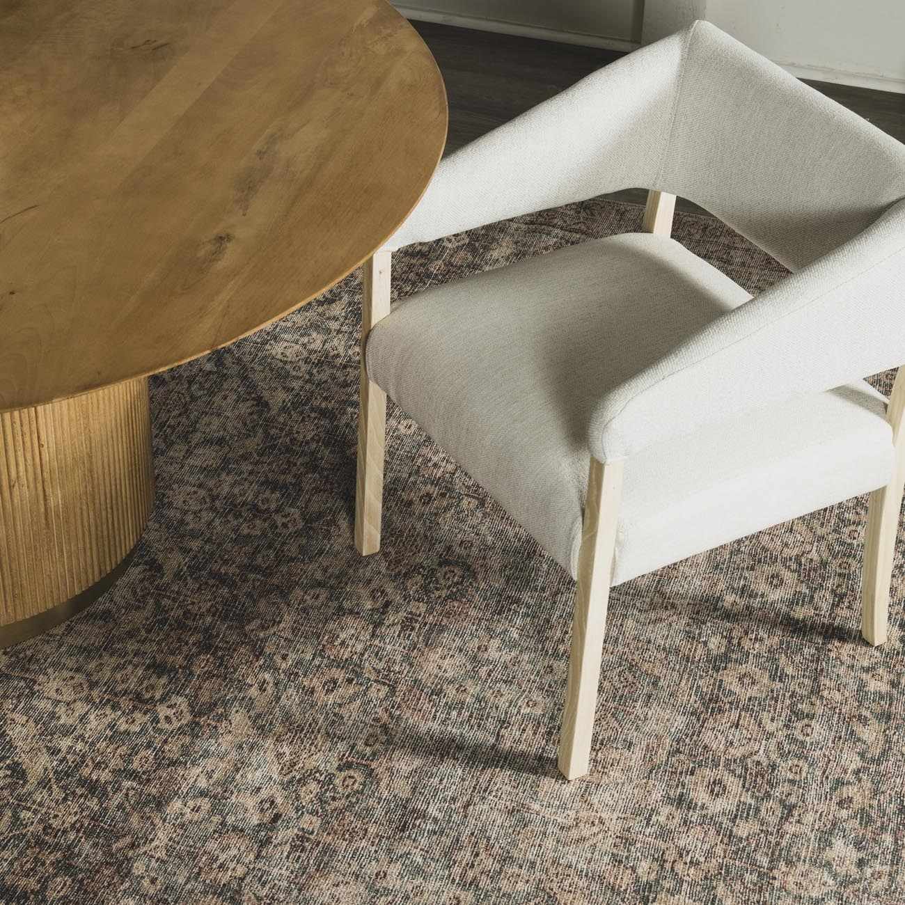 Close-up of the beige and dark red Collins Avenue III Vintage Damask Area Rug under a wood table and white chair. Styleshot