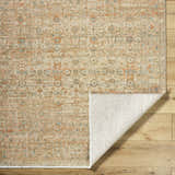 Close-up of Becki Denim Owens x Livabliss Renaissance Area Rug showing beige, coral, and denim traditional pattern and wool texture. Fold