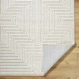 Close-up of the Briana Beige Washable Area Rug showing its geometric pattern, texture, and non-slip backing. Fold
