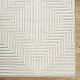 Close up of the Briana Beige Washable Area Rug. Beige and off-white geometric design with a textured, machine-woven construction. Corner