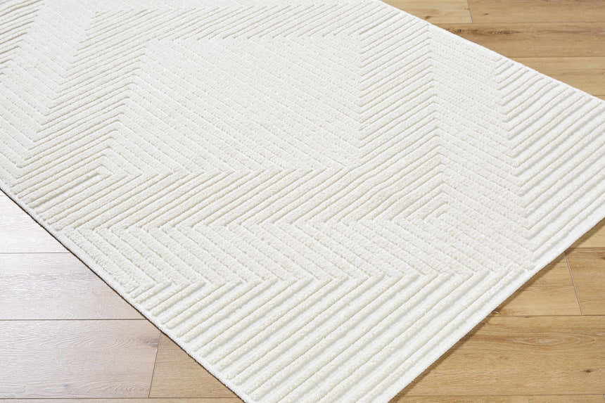 Close-up of the Briana Off-White Washable Area Rug. Cream rug with a geometric, raised zig-zag pattern and soft texture. Corner