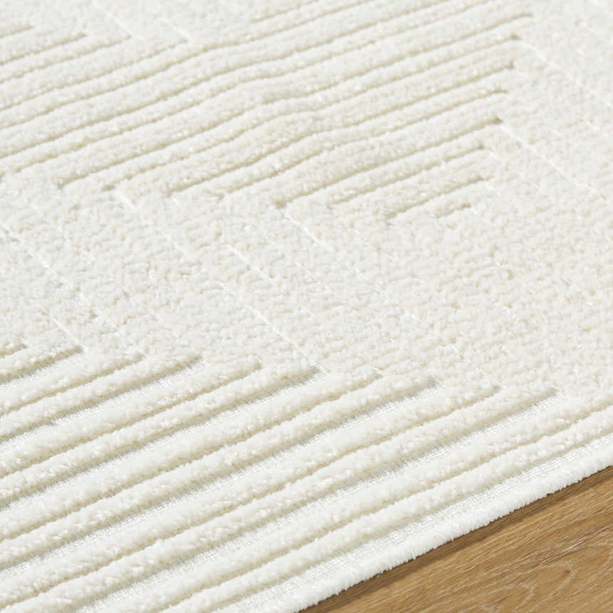 Close up of the Briana Off-White Washable Area Rug. Cream rug with a geometric, raised line pattern and soft, textured pile. Texture