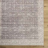 Close-up of the Spokane Dark Brown Area Rug showing its traditional floral pattern and dark brown, cream, and peach colors. Corner