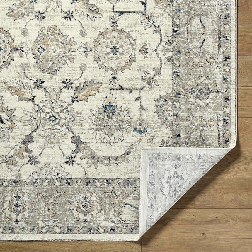 Close-up of the Yume Ivory Persian Rug showing its traditional floral pattern, charcoal, olive, and taupe colors. Fold
