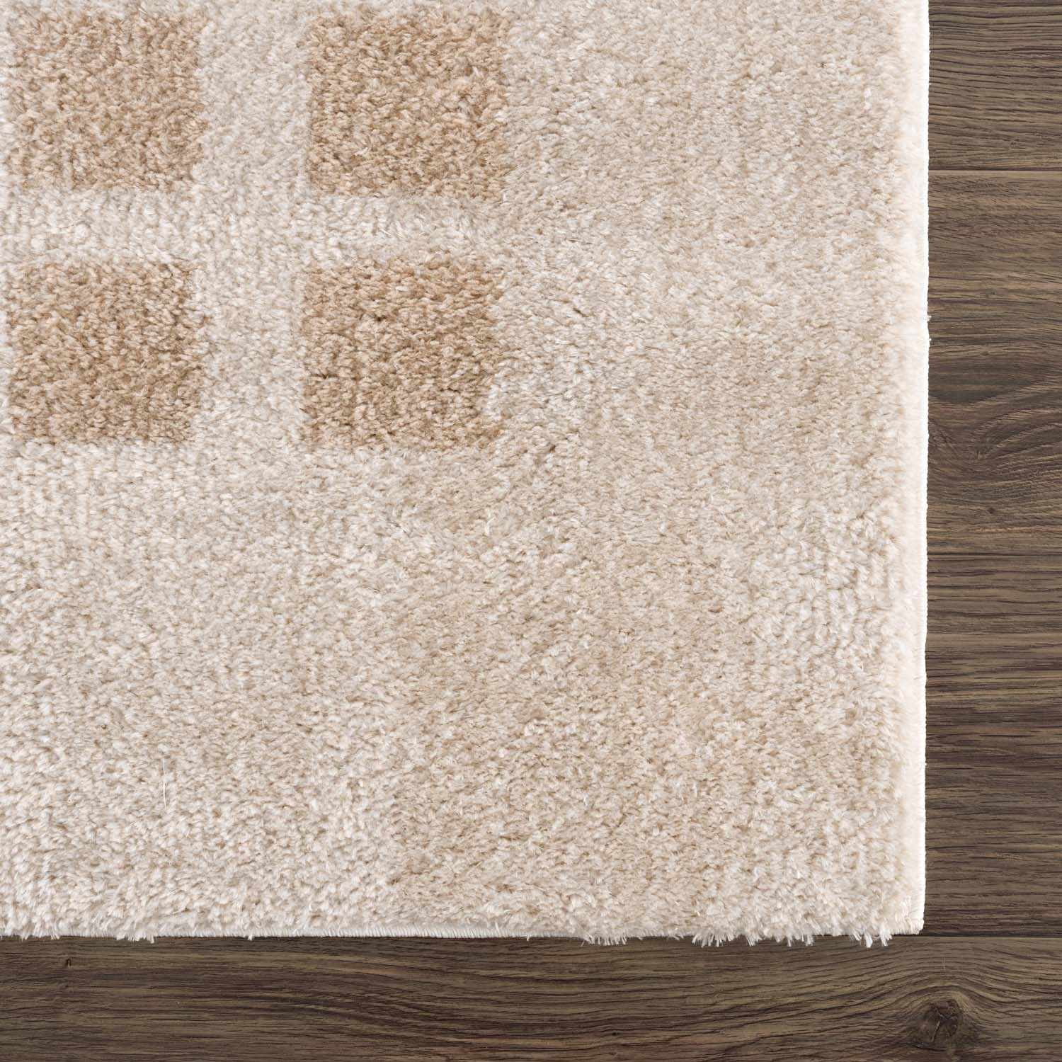 Close-up of the Baback Beige Washable Area Rug showing the soft texture and beige square pattern on a wood floor. Corner