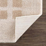 Close-up of the Baback Beige Washable Area Rug showing the beige and peach square pattern, plush texture, and non-slip backing. Fold