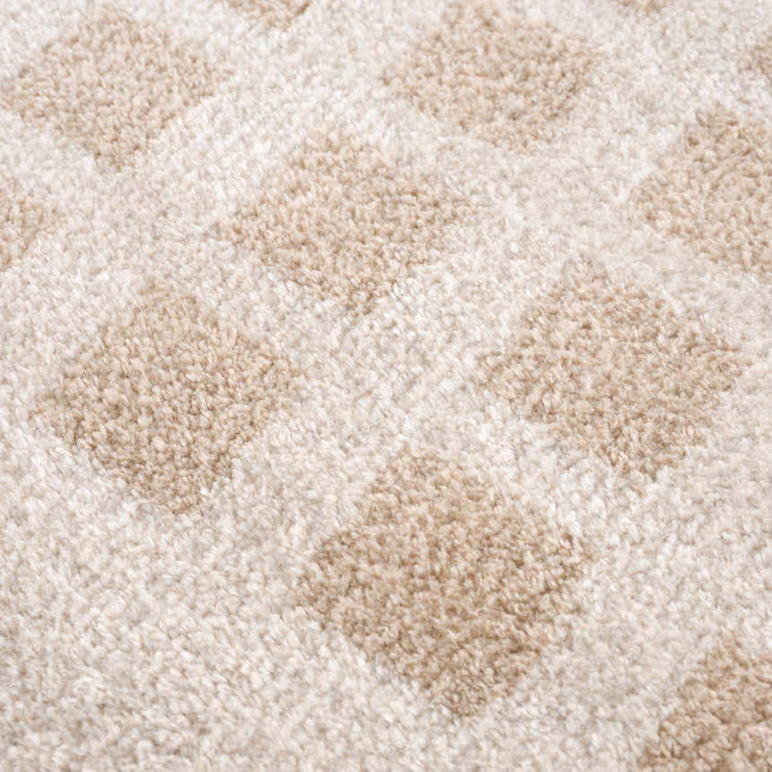 Close-up of the Baback Beige Washable Area Rug, showing a textured, geometric diamond pattern in beige and peach tones. Texture