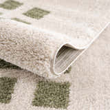 Close-up of the Baback Green Washable Area Rug showing lime green squares on a plush, cream-colored polyester rug. Fold