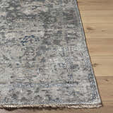 Close up of the Ballantrae Premium Rug showing its beige, charcoal, and blue traditional pattern and fringe. Front