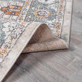 Close-up of the Bolinas Area Rug showing its traditional pattern, brick red, camel, and sky blue colors, and machine-woven construction. Fold