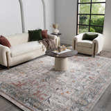 Living room scene with a Bolinas Area Rug, cream sofa, armchair, and round coffee table. The rug features brick red, gray, and pink tones. Roomscene-Rectangle