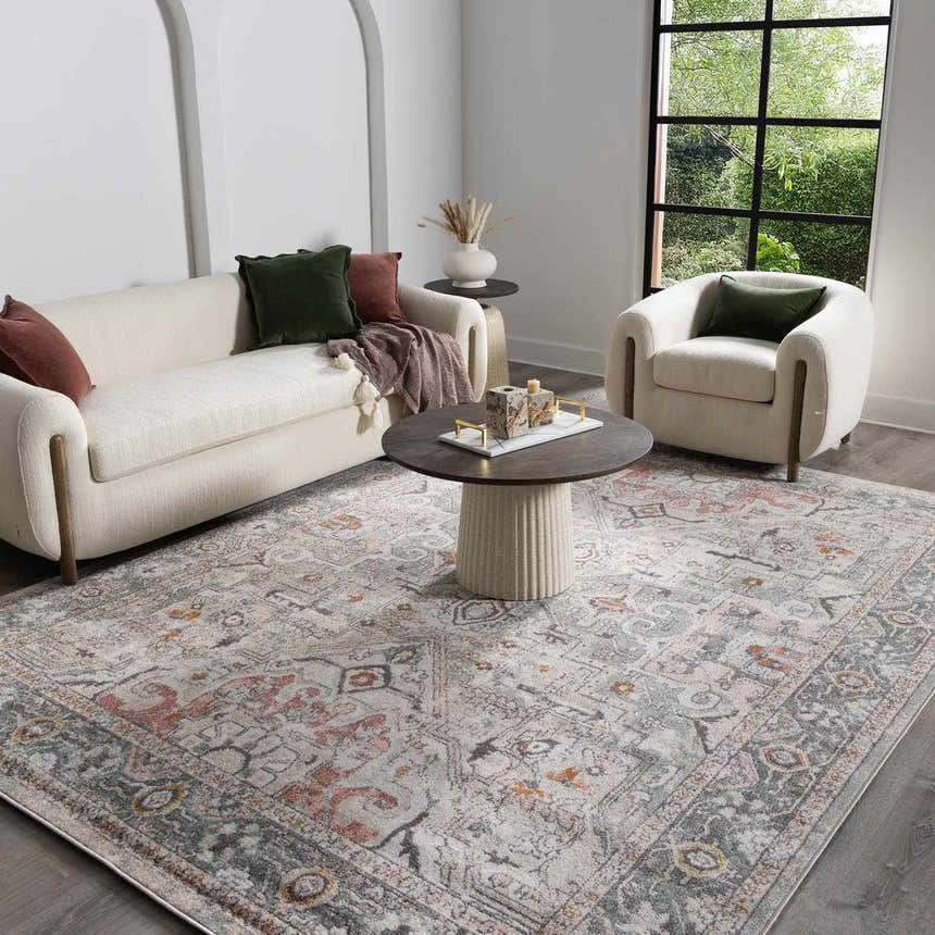 Living room scene with a Bolinas Area Rug, cream sofa, armchair, and round coffee table. The rug features brick red, gray, and pink tones. Roomscene-Rectangle