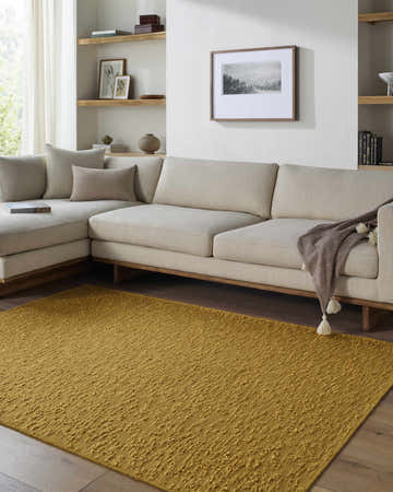 Living room scene with a goldenrod Breena Washable Area Rug, beige sectional sofa, and wood accents. Roomscene-Rectangle