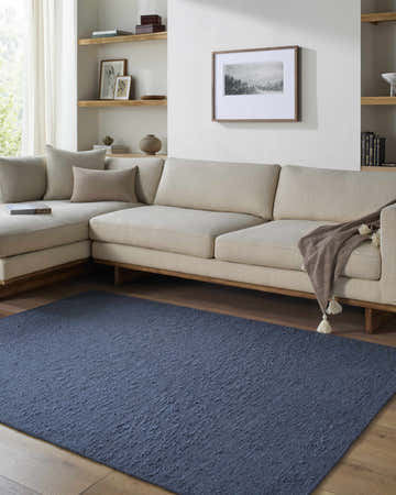 Living room scene with a beige sectional sofa and indigo Breena Washable Area Rug on hardwood floors. Roomscene-Rectangle
