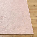 Close-up of the hand-woven Breena Blush Washable Area Rug showing texture and blush color on wood floor. Front