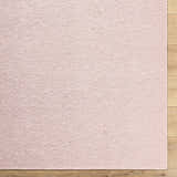 Close-up of the Breena Blush Washable Area Rug showing the texture and blush color on a wood floor. Corner