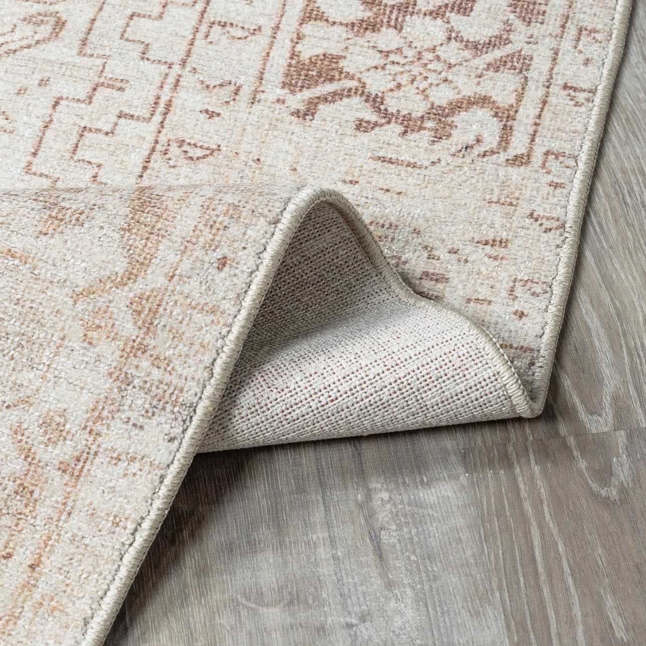 Close-up of the Galey Alix Collins Avenue Vintage Medallion Rug. Beige, dark red, and ivory vintage pattern detail. Fold