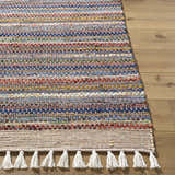 Close-up of the hand woven Brenda Indigo Area Rug. Features indigo, rust, and mustard horizontal stripes and white tassels. Front