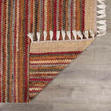 Close-up of the hand woven Brenda Crimson Area Rug. Farmhouse style rug with red, orange, and tan stripes and white tassels. Fold