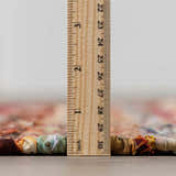 Close-up of the Brenda Crimson Area Rug showing the rug's thickness with a ruler. Pile