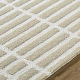 Close-up of the Bendek Beige Area Rug. Features a contemporary beige and ivory striped design with a hand-tufted, textured wool pile. Texture