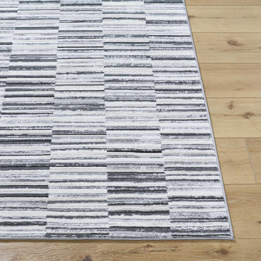 Close-up of Bronco Broken Striped Area Rug. Contemporary design with black, charcoal, gray, and ivory stripes. Front