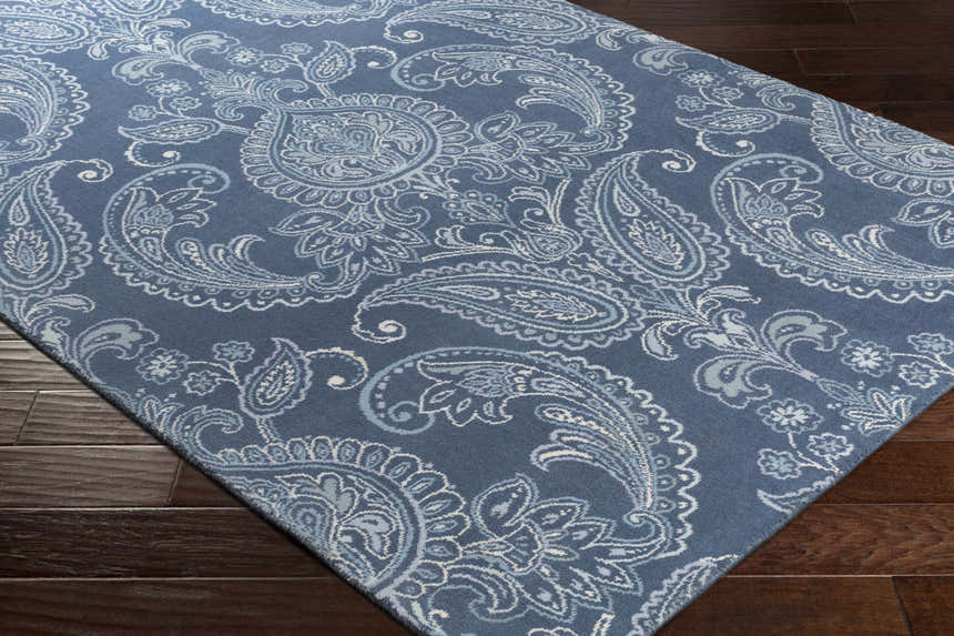 Close-up of the Simpatico Candice Olson x LIVABLISS SPO-1000 Area Rug. Blue wool rug with a white and pale blue paisley pattern. Corner