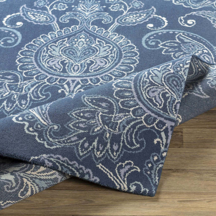 Close-up of the Simpatico Candice Olson x LIVABLISS SPO-1000 Area Rug. Navy rug with cream, light blue, and sage paisley pattern. Fold