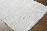 Close-up of the cream and ivory Aramis Area Rug showing its contemporary, textured, machine-woven design. Corner