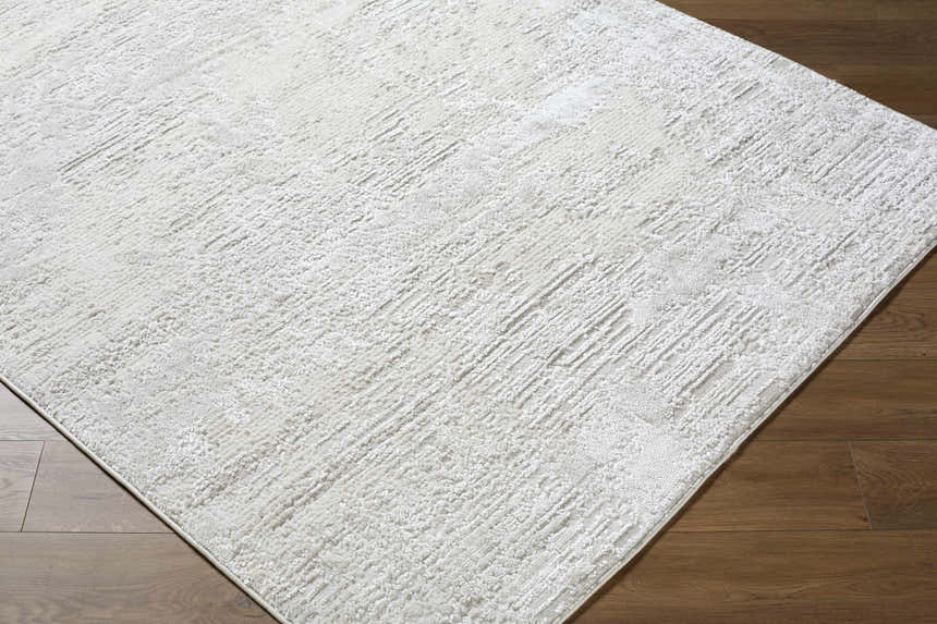Close-up of the cream and ivory Aramis Area Rug showing its contemporary, textured, machine-woven design. Corner