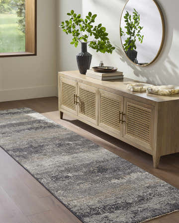 Entryway with a Behzad Medium Gray Area Rug runner, wood floors, and a light wood cabinet with a round mirror. Roomscene-Runner