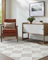 Living room scene with orange chair and Bosley Beige Washable Area Rug featuring a cream and beige checkerboard pattern. Roomscene-Rectangle
