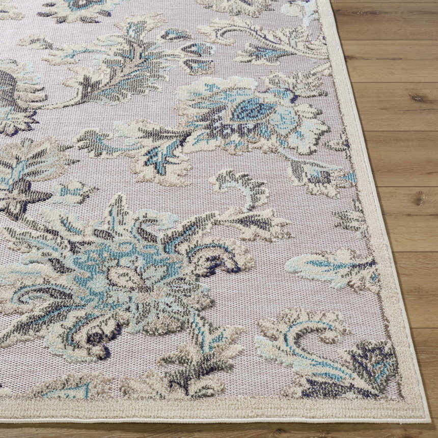Close up of the Benita Area Rug showing aqua, cream, and light brown floral pattern and woven texture on wood floor. Front