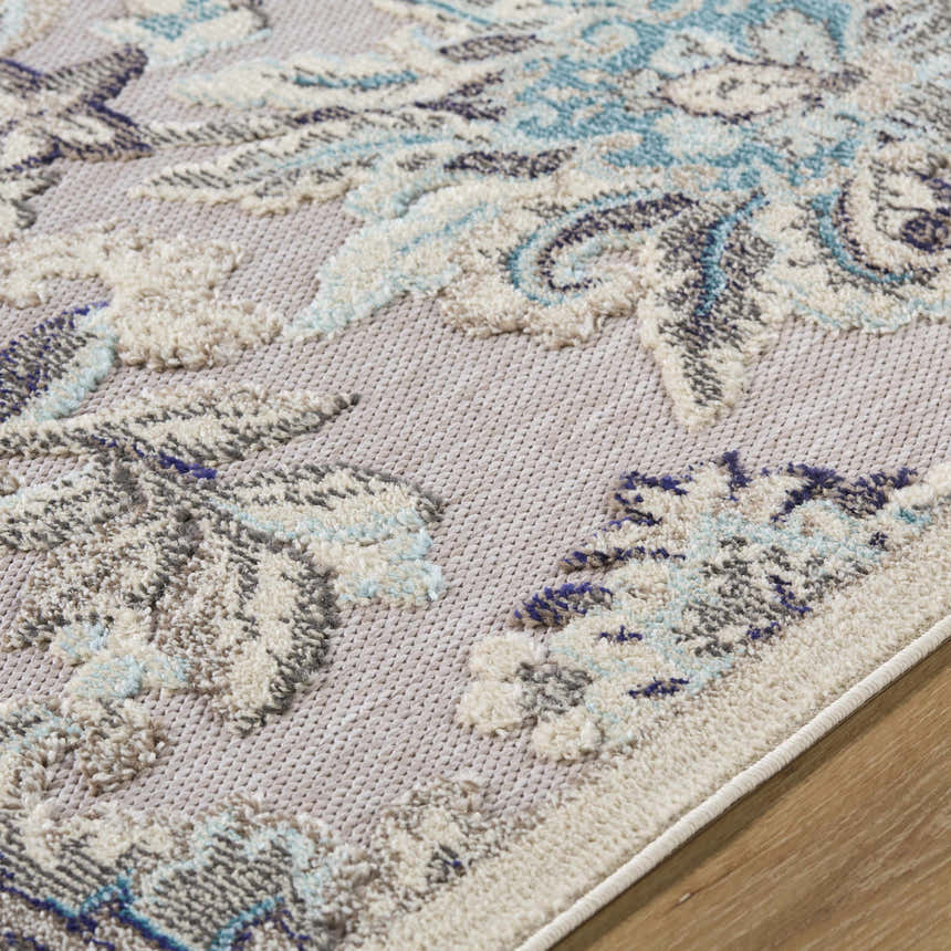 Close up of the Benita Area Rug showing aqua, cream, and navy floral pattern and woven texture. Texture