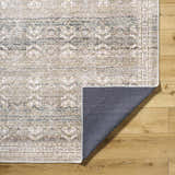 Close-up of Billie Vintage Flat Pile Washable Rug. Cream, green, and peach traditional pattern on a polyester rug. Fold