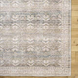 Close-up of the Billie Vintage Flat Pile Washable Rug. Traditional design in cream, green, olive, and peach tones. Corner