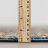 Close-up of the Neola Navy Blue Damask Area Rug showing rug thickness with a ruler. Pile