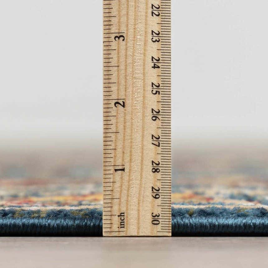 Close-up of the Neola Navy Blue Damask Area Rug showing rug thickness with a ruler. Pile